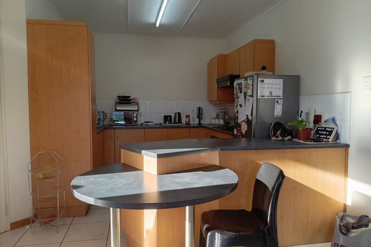A functional kitchen featuring laminate cabinetry, tiled flooring, and a breakfast nook, offering a practical layout for daily meal preparation.
