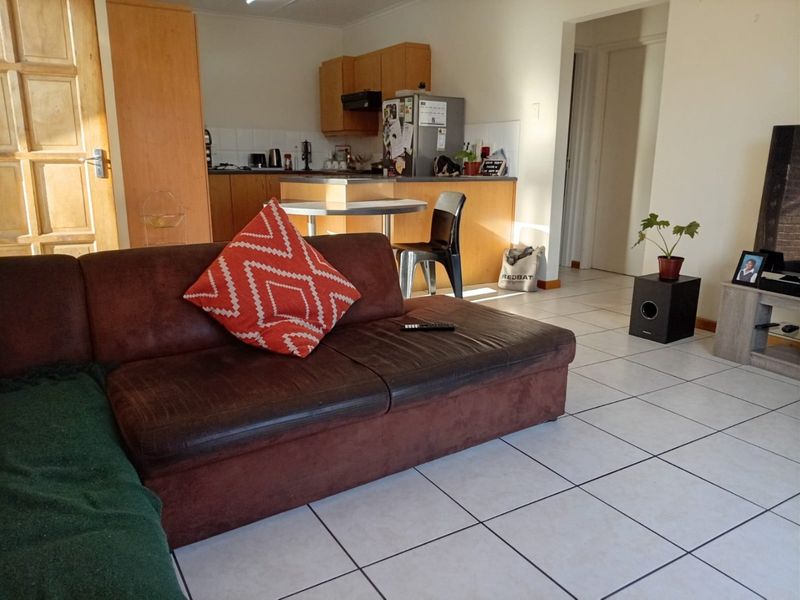 Open plan living area featuring tiled flooring and a functional kitchen with built-in cabinetry and a tiled backsplash.
