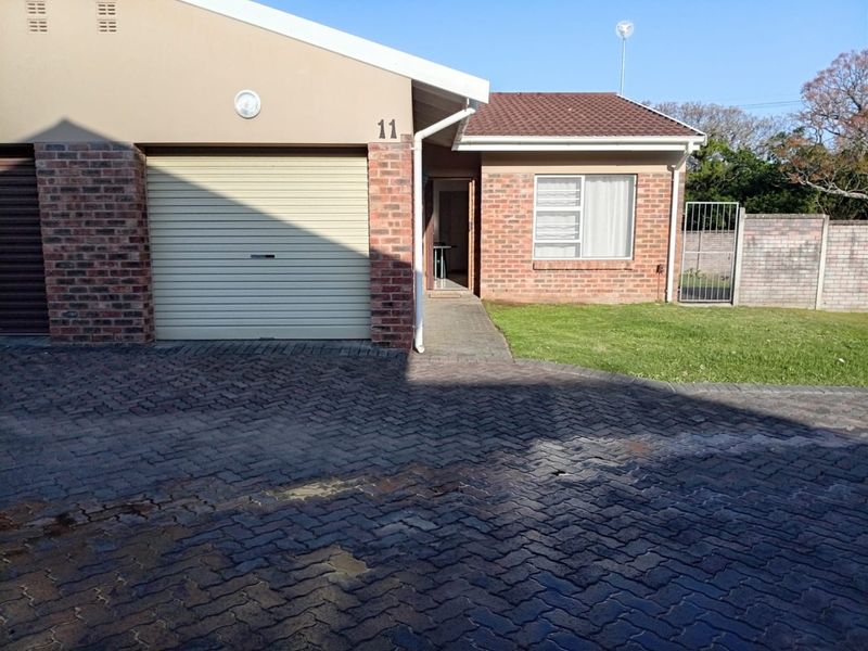 Front exterior view of a townhouse featuring a brick facade, a single roller garage door, and a paved driveway with a small front lawn.