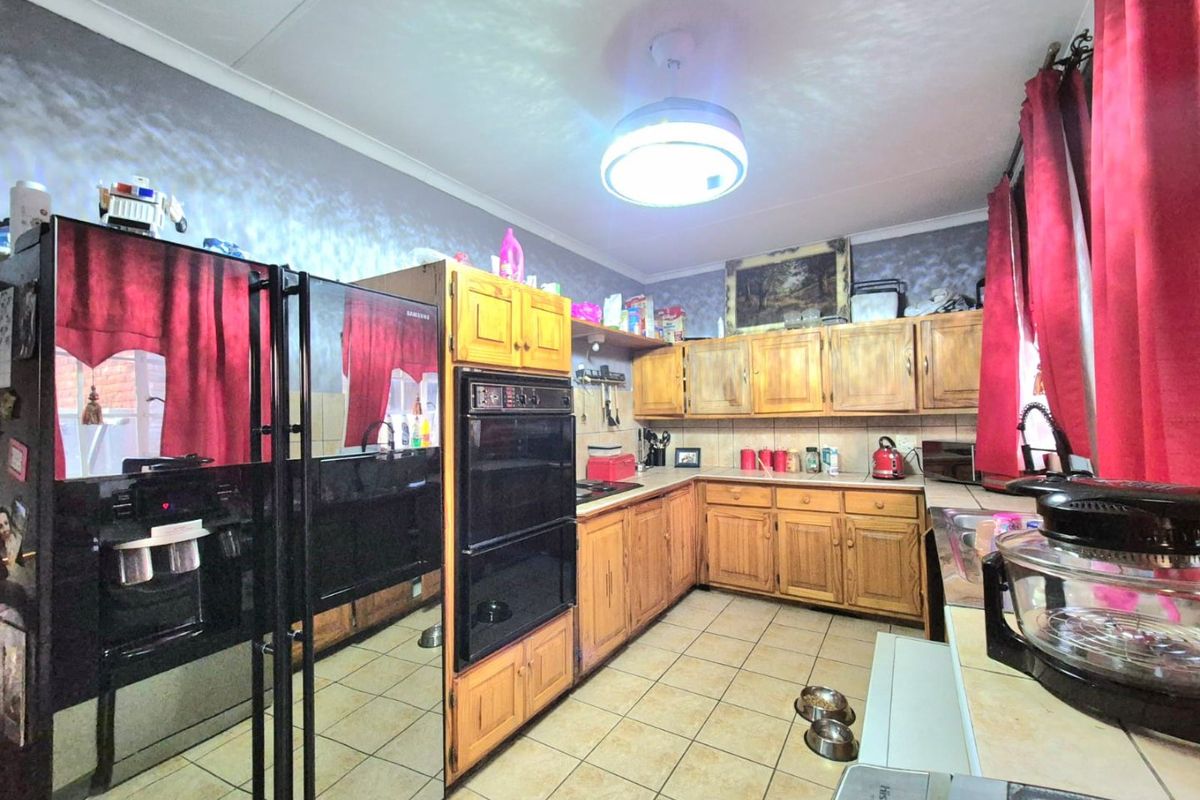 A functional kitchen featuring traditional wooden cabinetry, a built-in double oven, tiled backsplash, and ceramic floor tiles.