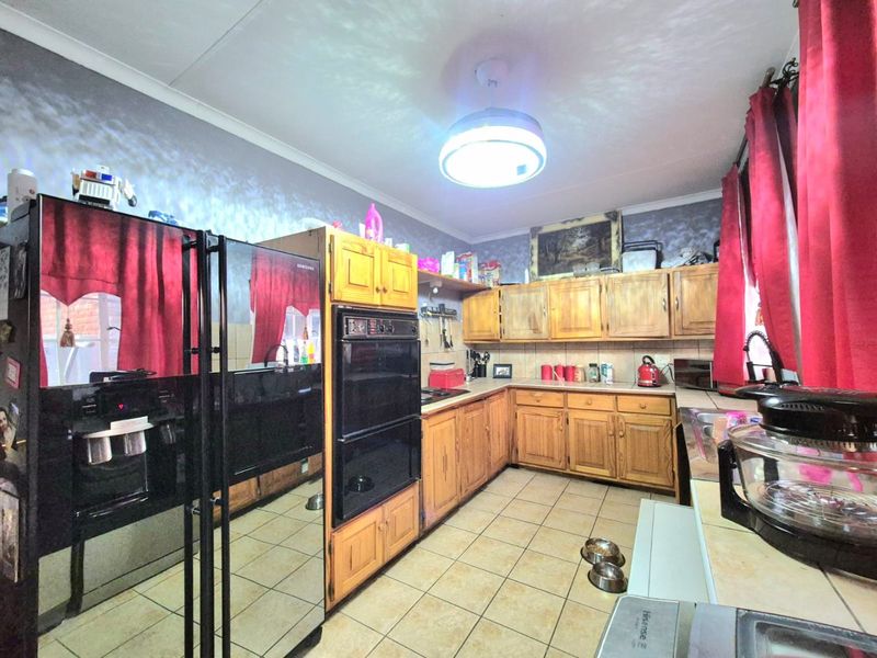 A functional kitchen featuring traditional wooden cabinetry, a built-in double oven, tiled backsplash, and ceramic floor tiles.