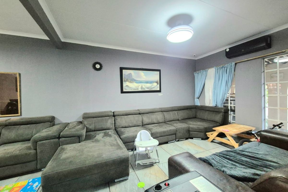 A living room featuring tiled flooring, a wall-mounted air conditioning unit, and a sliding door leading to the exterior.
