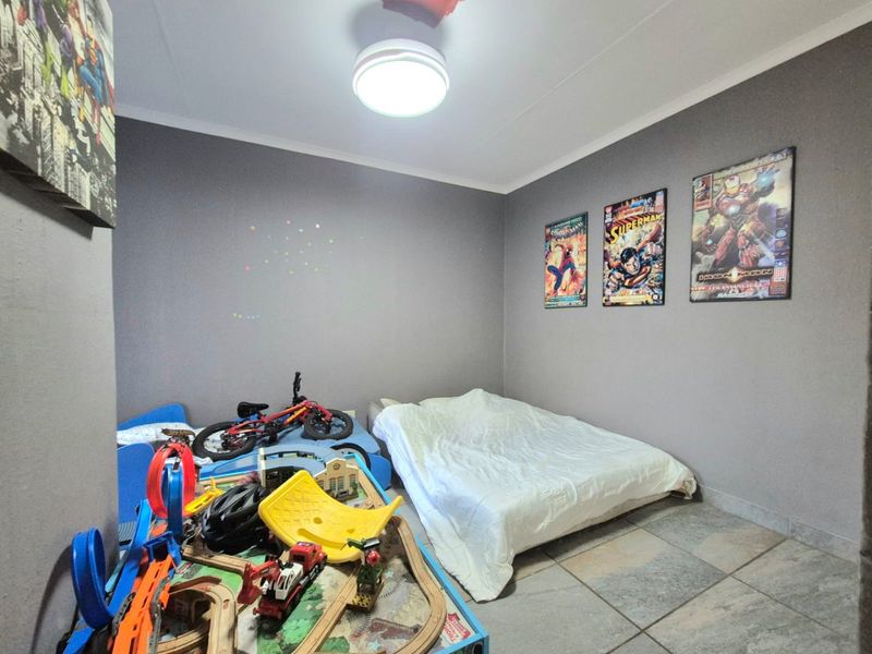 A bedroom featuring tiled flooring and neutral grey walls, providing a functional space for rest.