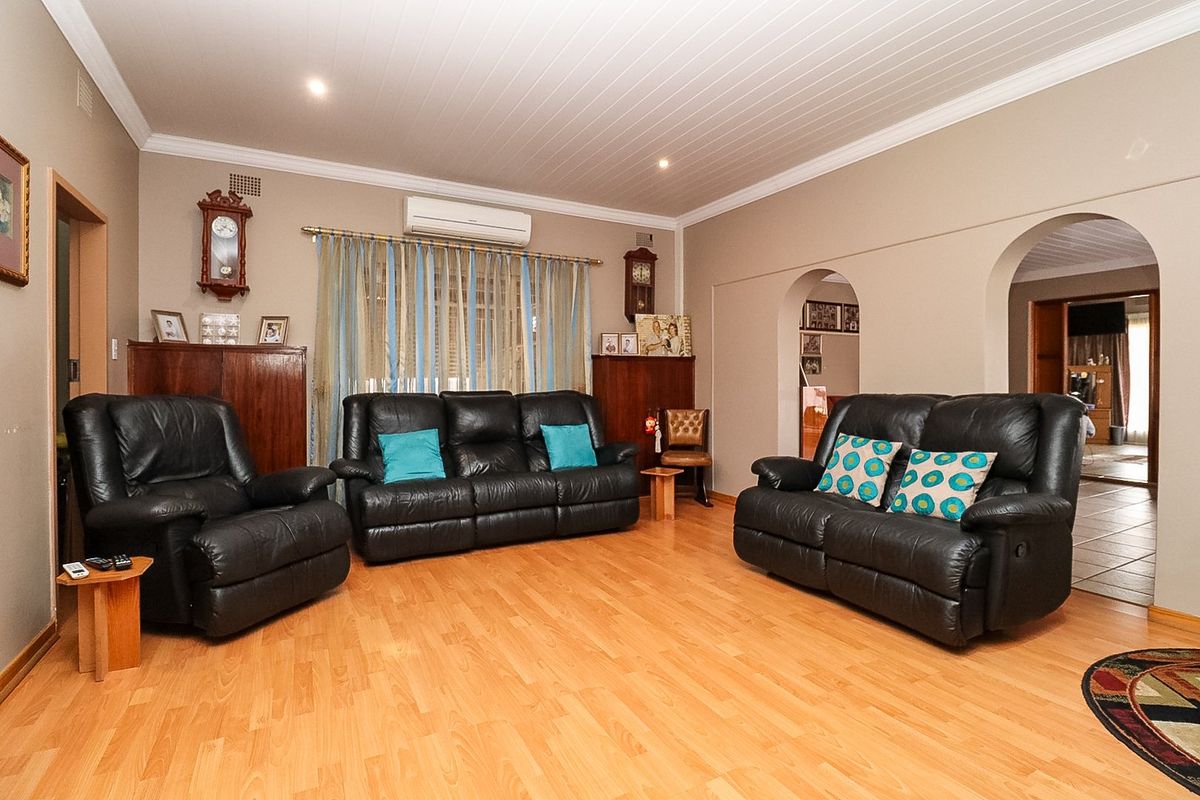 Spacious living room featuring laminate flooring, a tongue and groove ceiling, and an integrated split system air conditioner with classic archway transitions.