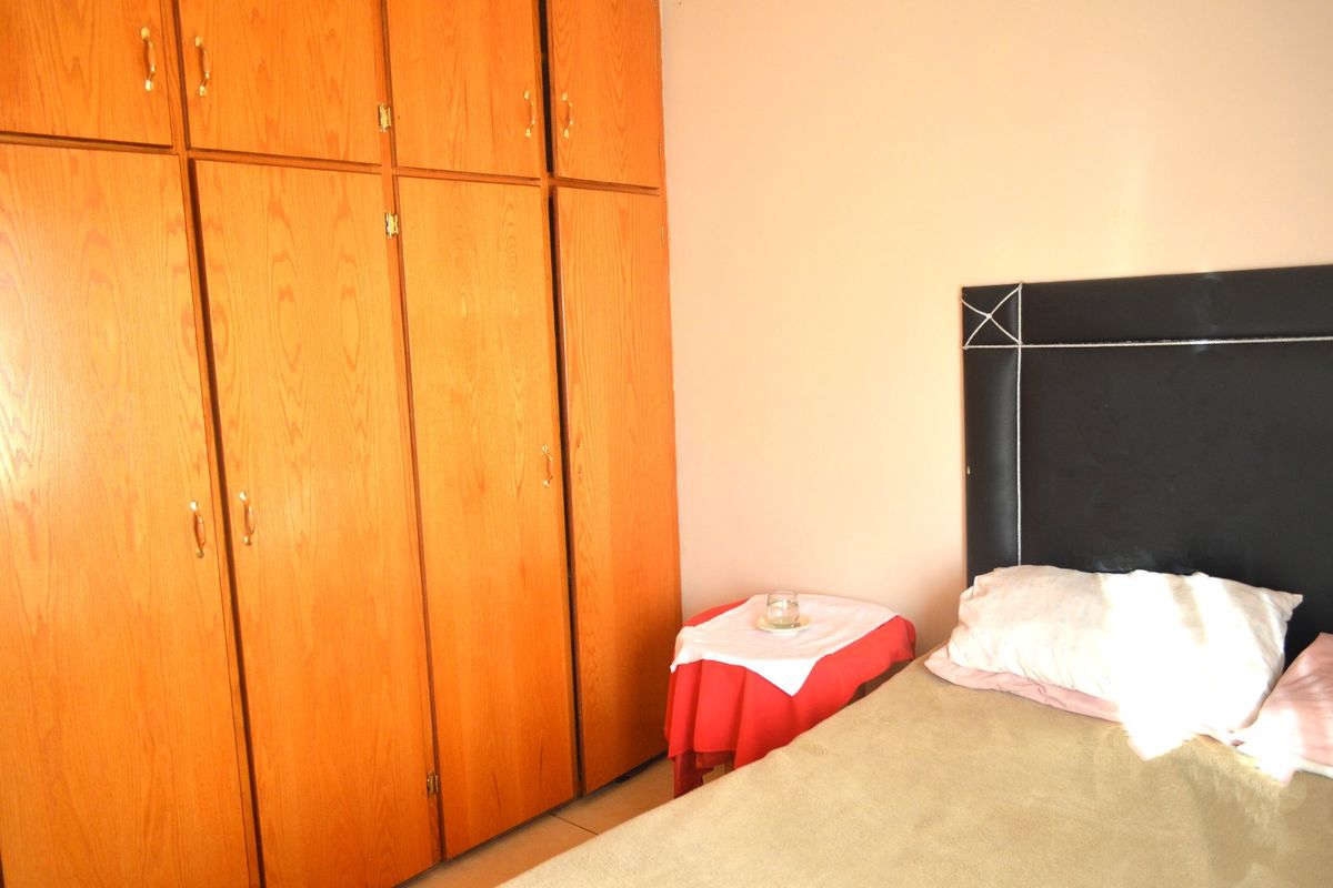 A bedroom featuring floor-to-ceiling built-in wooden wardrobes providing ample storage space.