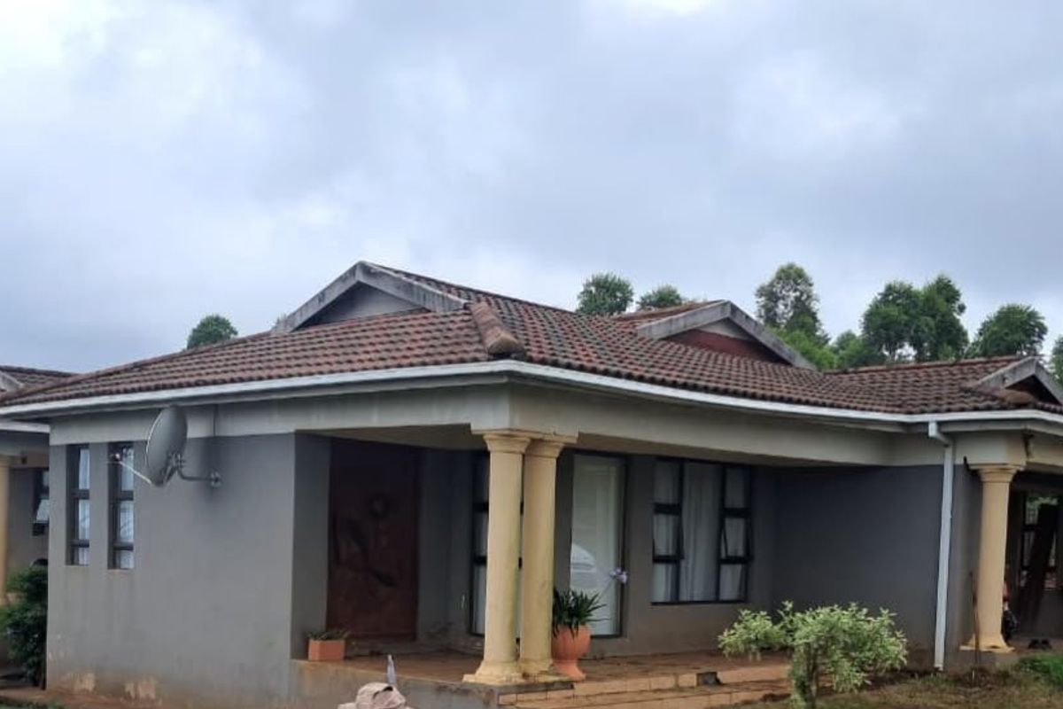 A single-story residential house featuring a tiled roof, covered patio with concrete columns, and tiled entrance steps.