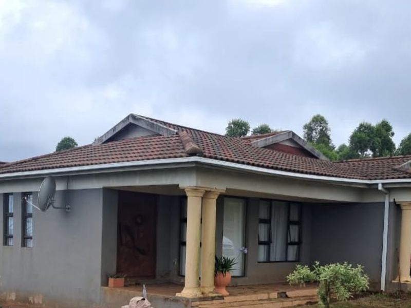 A single-story residential house featuring a tiled roof, covered patio with concrete columns, and tiled entrance steps.