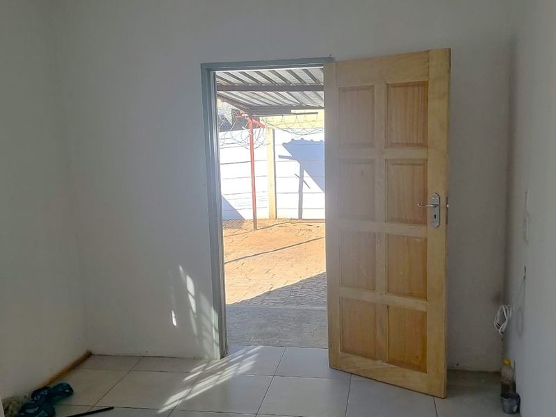 An empty bedroom featuring tiled flooring and a wooden door leading to an outdoor area.