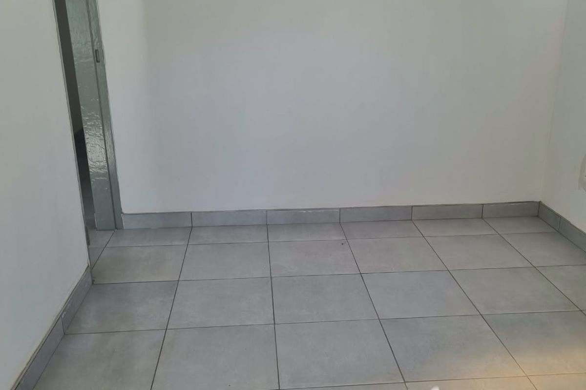 A clean, empty room featuring neutral ceramic floor tiles and white walls, providing a versatile blank canvas for any interior design style.
