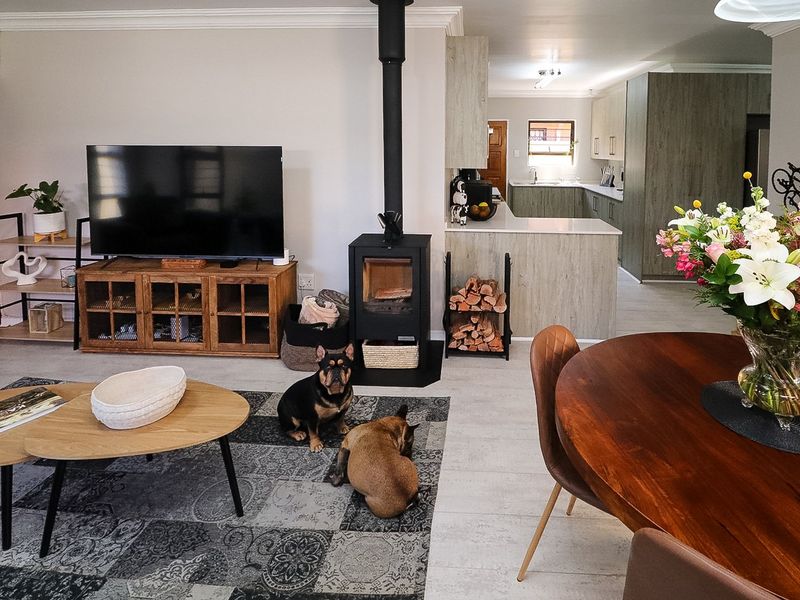 Open-plan living and dining area featuring a modern freestanding fireplace, tiled flooring, and a contemporary kitchen with stone countertops.