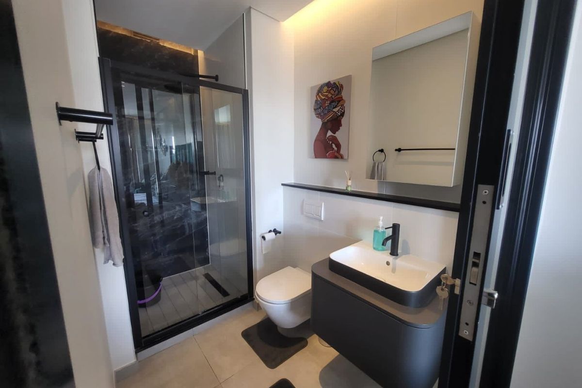 Modern bathroom featuring a walk-in shower with glass enclosure, wall-hung toilet, and a sleek vanity with a vessel sink and black fixtures.
