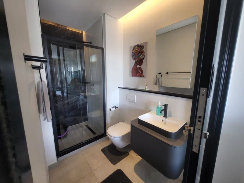Modern bathroom featuring a walk-in shower with glass enclosure, wall-hung toilet, and a sleek vanity with a vessel sink and black fixtures.