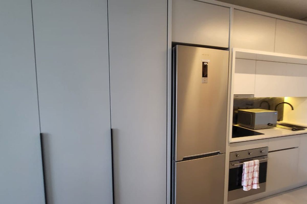 Modern kitchen featuring sleek built-in cabinetry, stainless steel appliances, and a clean stone countertop finish.