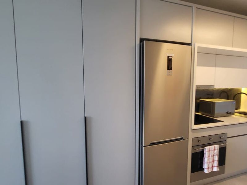 Modern kitchen featuring sleek built-in cabinetry, stainless steel appliances, and a clean stone countertop finish.