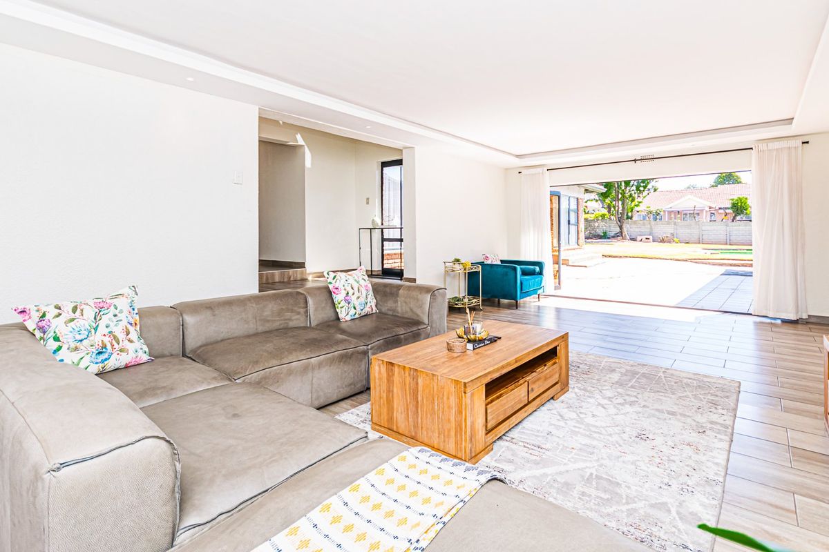 Spacious living room featuring tiled flooring, recessed lighting, and large sliding glass doors that provide seamless access to the outdoor patio area.