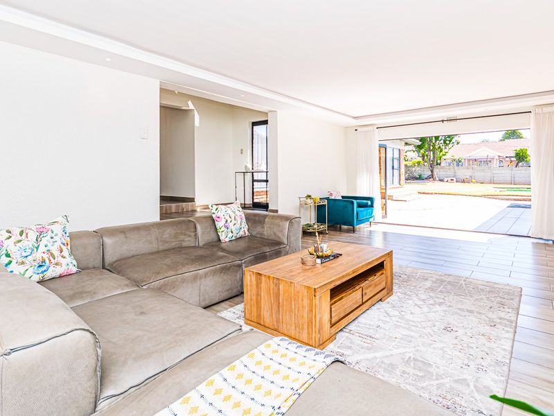 Spacious living room featuring tiled flooring, recessed lighting, and large sliding glass doors that provide seamless access to the outdoor patio area.
