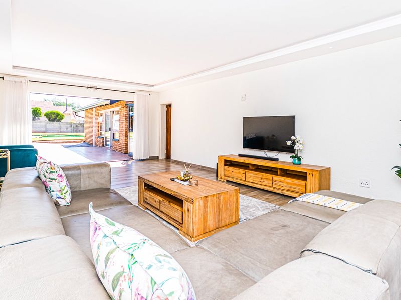 Spacious living room featuring laminate flooring, recessed ceiling lighting, and large sliding glass doors providing seamless access to the outdoor patio area.
