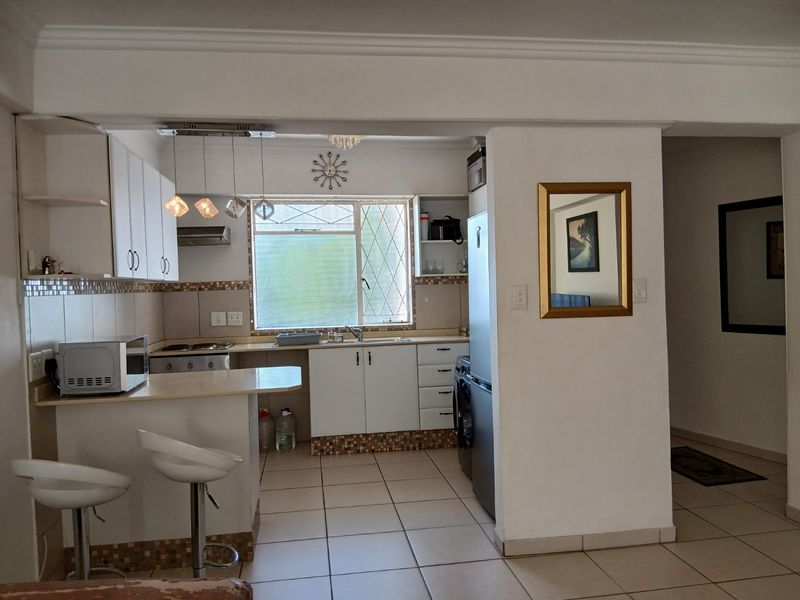 A functional kitchen featuring white cabinetry, tiled backsplash, a breakfast counter, and integrated appliances, offering a practical layout for daily use.