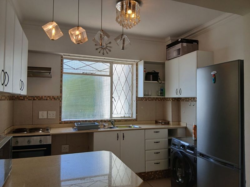 A functional kitchen featuring white cabinetry, stone countertops, a built-in oven and hob, and a window with security bars.