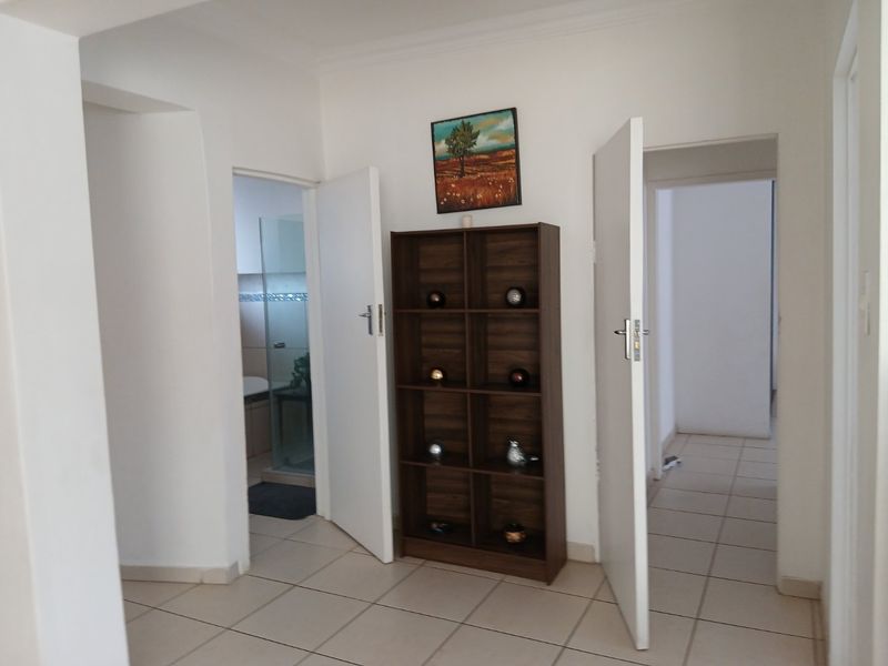 A neutral hallway featuring tiled flooring and access to multiple rooms, providing a clean and functional transition space within the apartment.