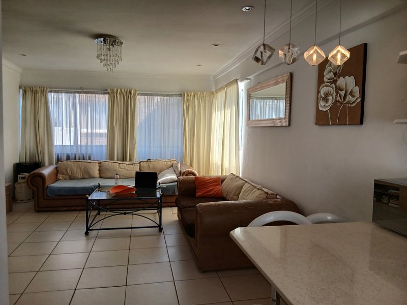 Open-plan living and dining area featuring tiled flooring, recessed lighting, and a stone countertop, offering a functional layout for modern apartment living.