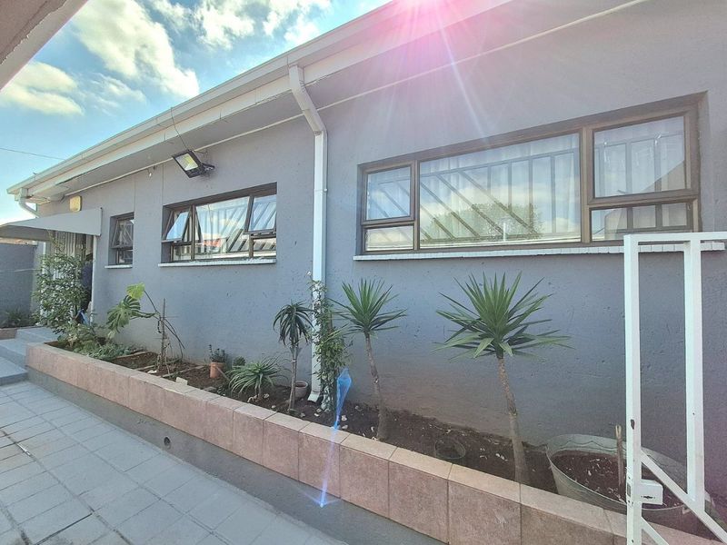 Rear exterior view of the property featuring a tiled planter box, security-fitted aluminium windows, and functional guttering systems.