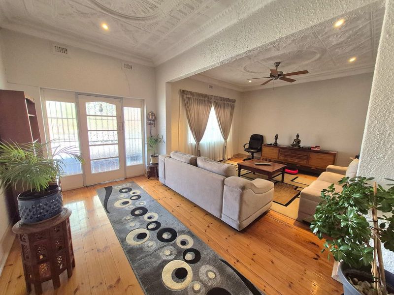 Spacious living area featuring original hardwood flooring and a decorative pressed metal ceiling, providing a classic character feel with integrated ceiling fan and lighting.