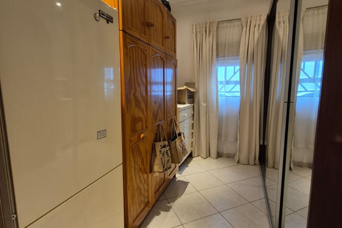 Bedroom featuring built-in wooden cabinetry, mirrored sliding wardrobes, tiled flooring, and a decorative pressed metal ceiling.