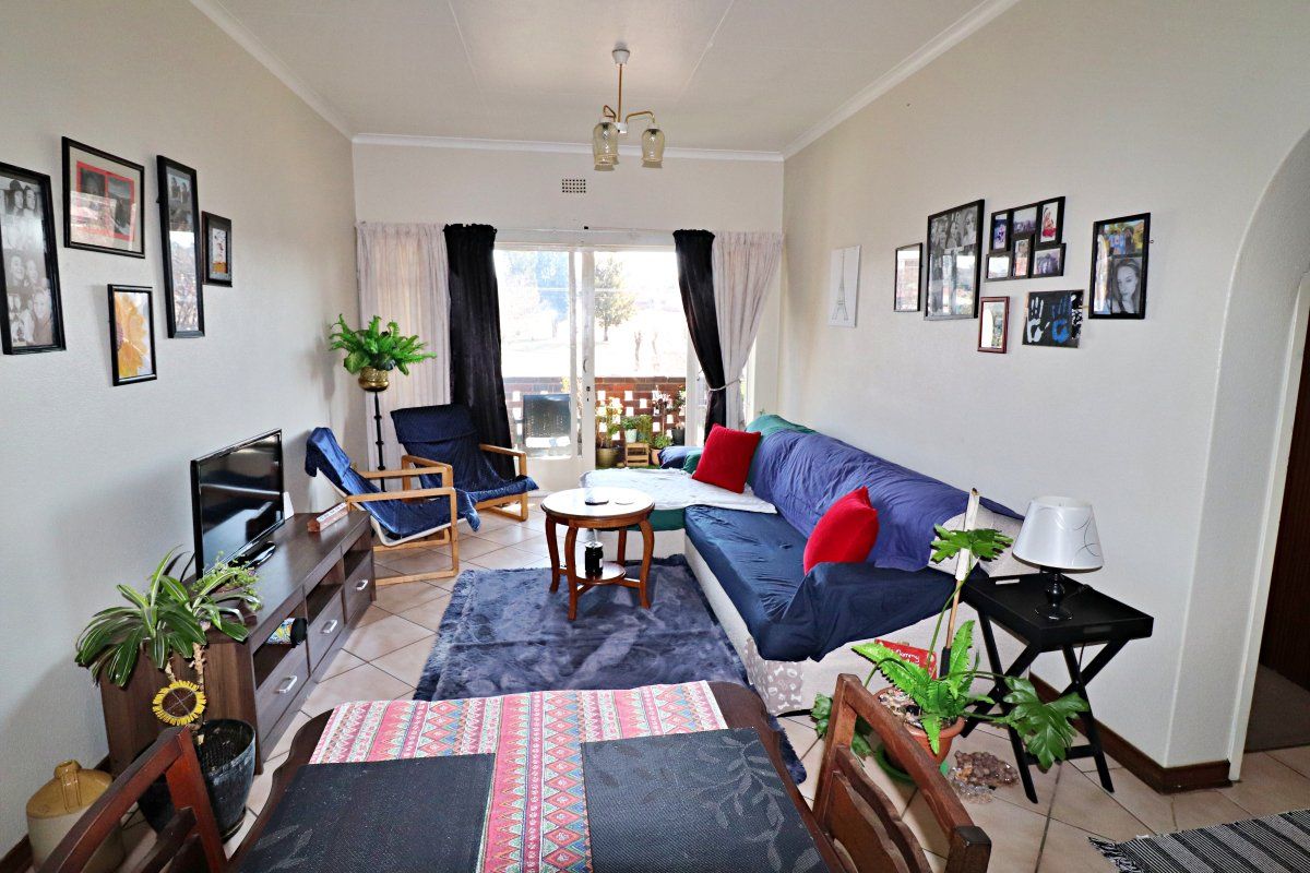 A functional living room featuring tiled flooring and a sliding glass door that provides access to an outdoor balcony area.