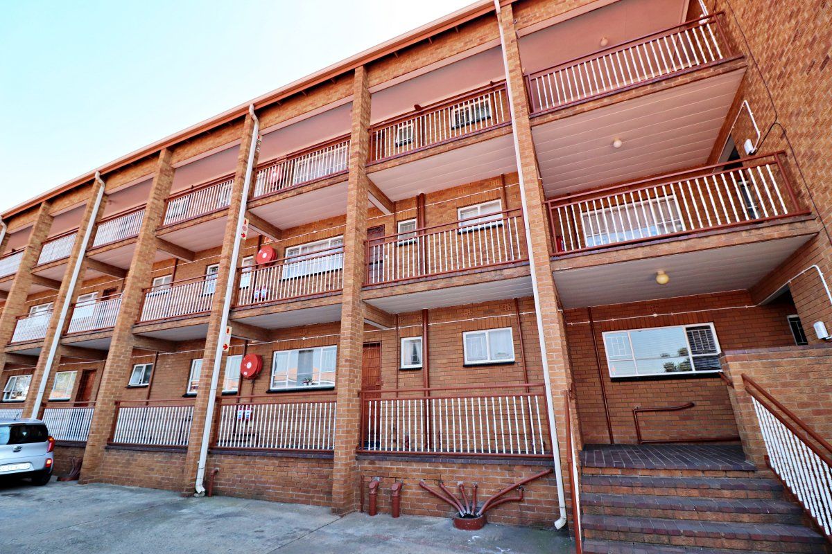 Multi-story apartment building exterior featuring face brick construction, private balconies with metal railings, and an external staircase.