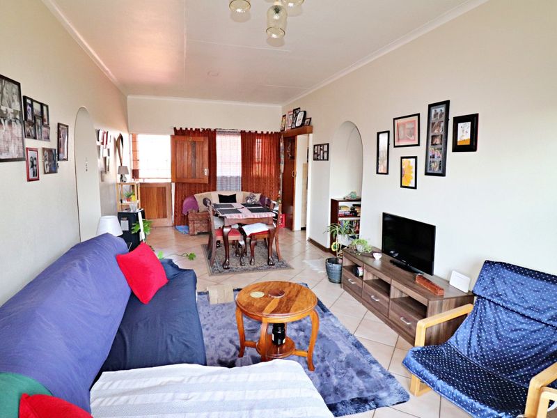 Open plan living and dining area featuring tiled flooring, coved ceilings, and arched doorways connecting to adjacent spaces.