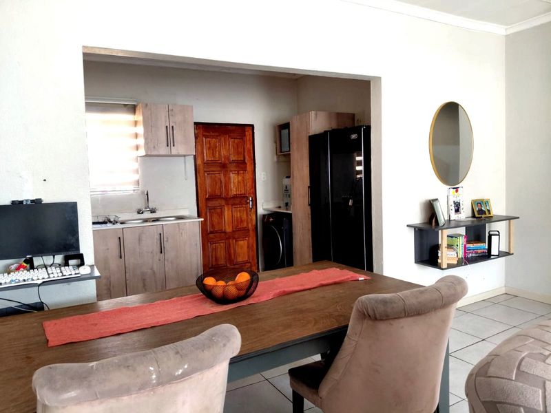 Open plan living and kitchen area featuring tiled flooring, built-in cabinetry, and a functional layout connecting the dining space to the kitchen.