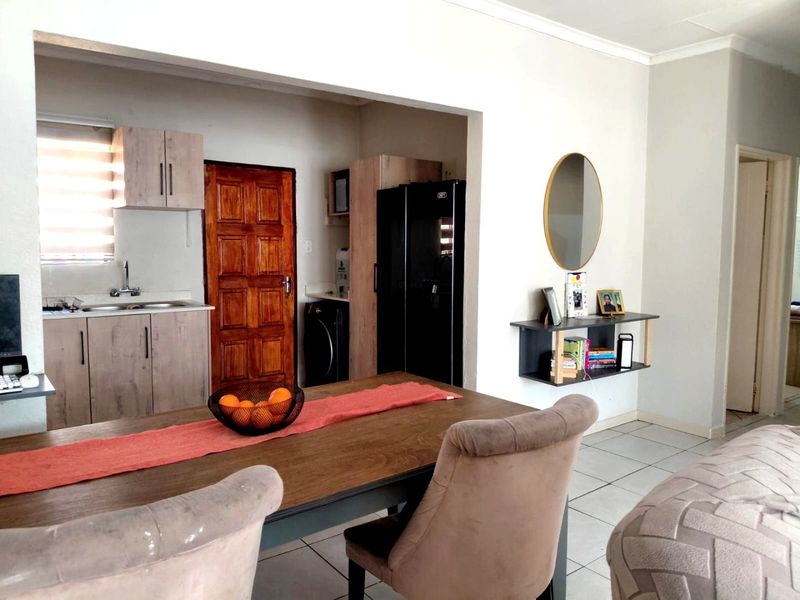 Open-plan living and dining area featuring a functional kitchen with wood-finish cabinetry and tiled flooring throughout.