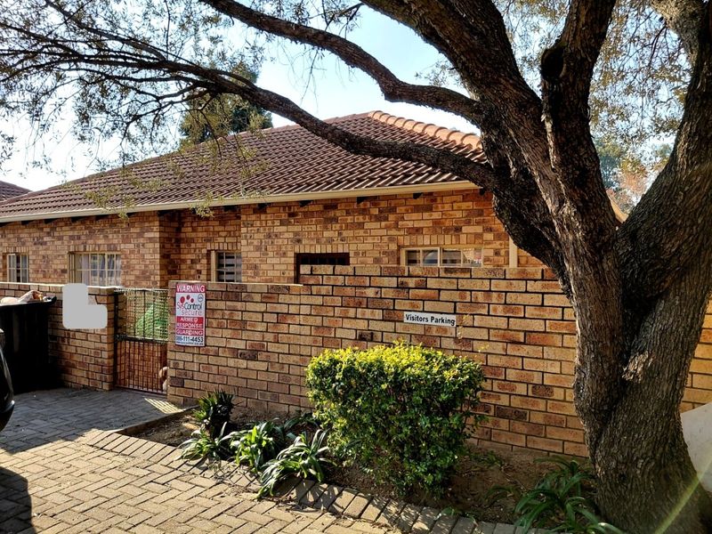 Front exterior view of a face brick house featuring a tiled roof, paved driveway, and secure boundary wall with gated access.
