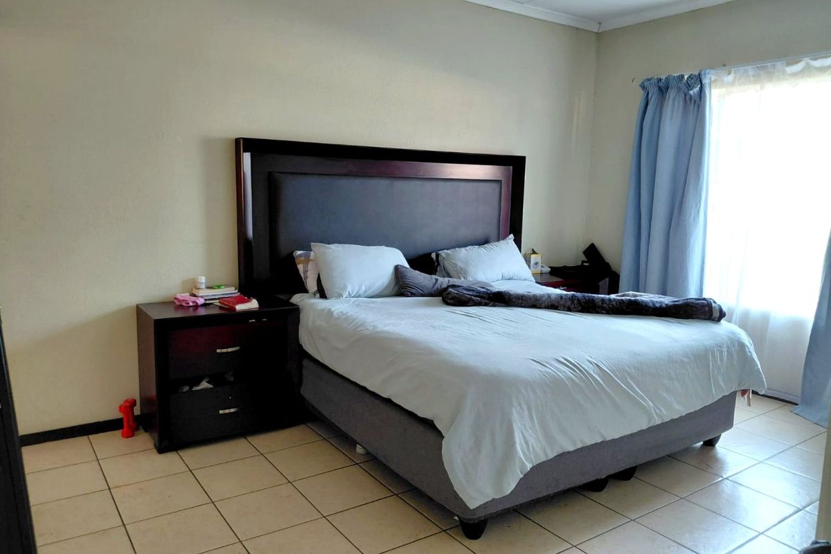 A functional bedroom featuring neutral wall finishes and tiled flooring, providing a blank canvas for potential interior updates.