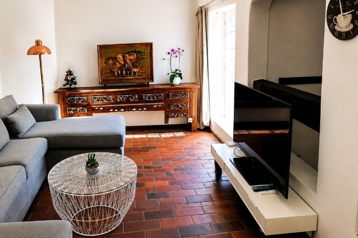 A cozy living room featuring traditional terracotta tile flooring and a distinctive arched architectural opening leading to an adjacent space.