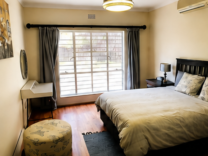 A well-maintained bedroom featuring laminate flooring, a split-system air conditioner, and large windows fitted with security bars for added peace of mind.