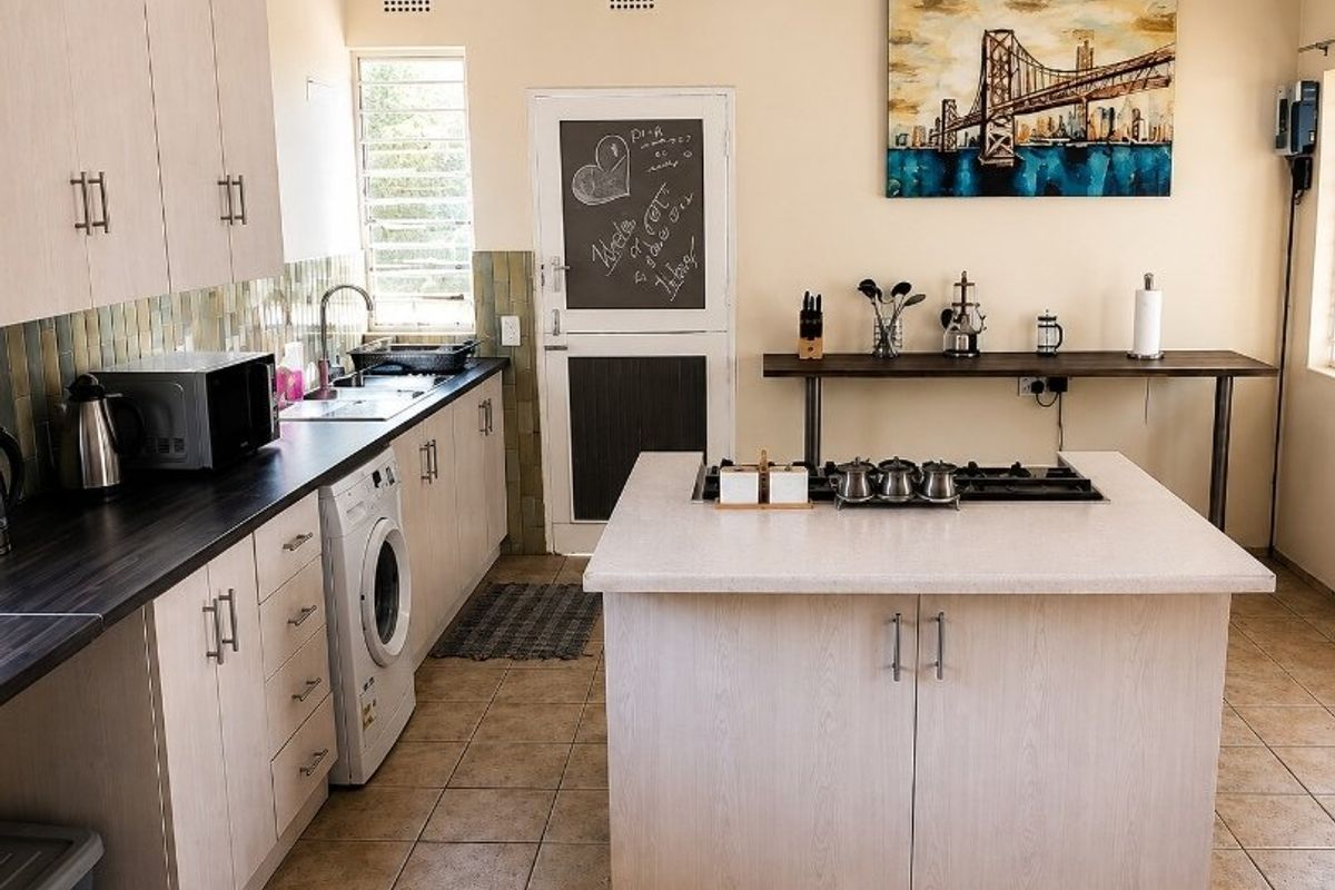 A functional kitchen featuring a central island with a gas cooktop, ample cabinetry, tiled backsplash, and integrated laundry space.