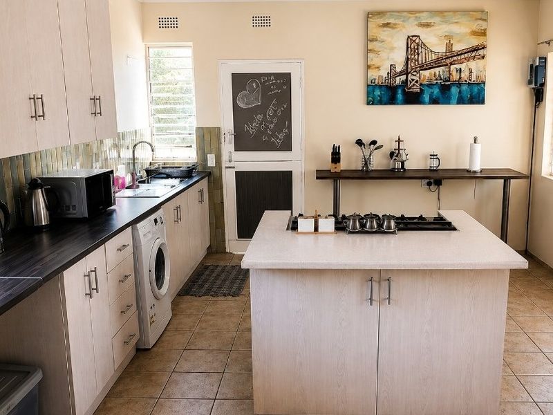 A functional kitchen featuring a central island with a gas cooktop, ample cabinetry, tiled backsplash, and integrated laundry space.