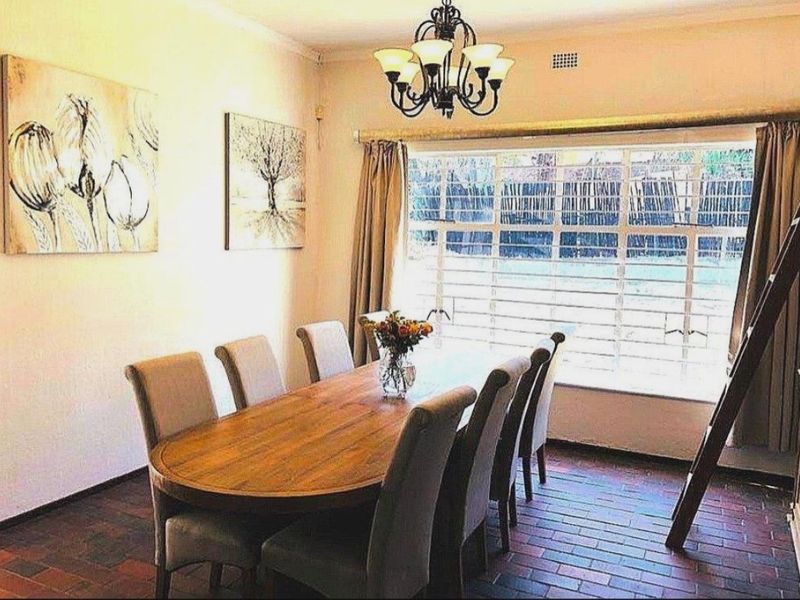 Dining room featuring traditional brick flooring, a decorative wrought iron chandelier, and a large window with integrated security bars.
