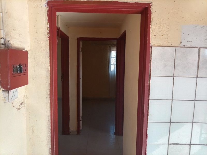 A narrow interior hallway showing signs of wear, featuring a wall-mounted electrical distribution board and tiled wall section.