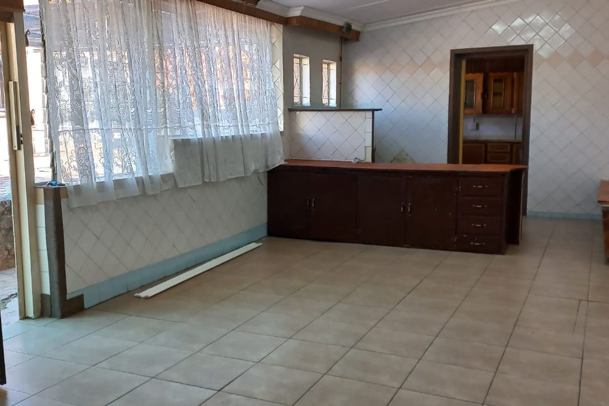 Spacious kitchen area featuring tiled flooring, wall tiling, and built-in cabinetry, offering a blank canvas for renovation and modernization.