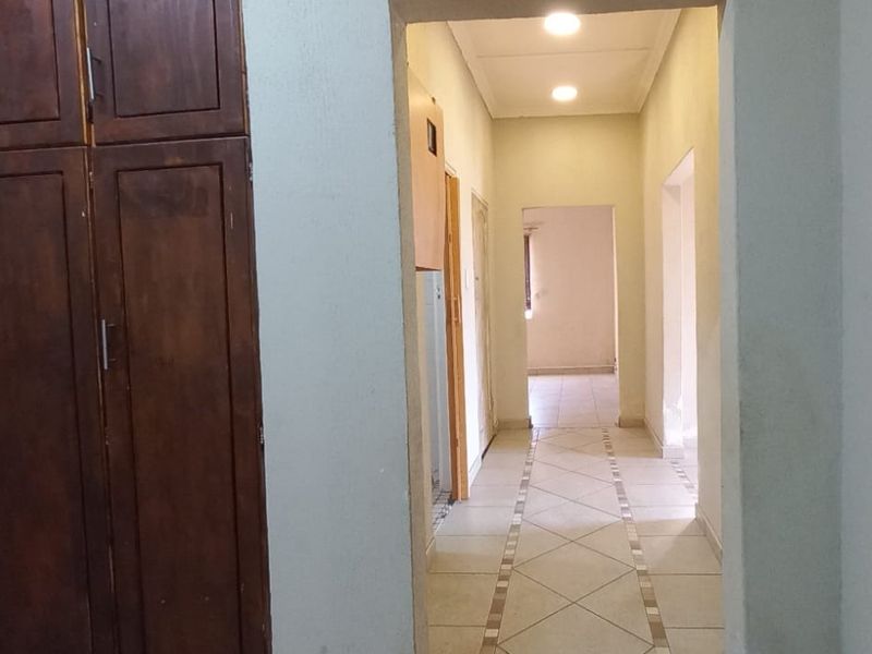 A functional hallway featuring built-in wooden cabinetry, tiled flooring, and recessed ceiling lighting, providing access to adjacent rooms.