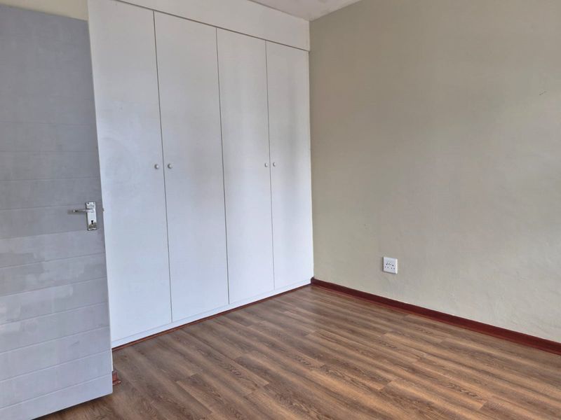 A vacant bedroom featuring laminate flooring, neutral wall tones, and ample built-in cupboard storage space.