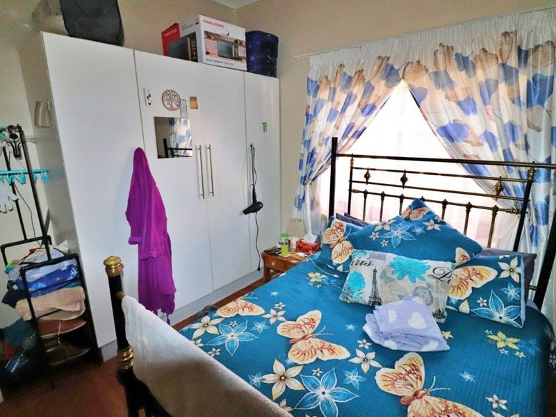 A bedroom featuring a built-in wardrobe and window with curtain treatments.
