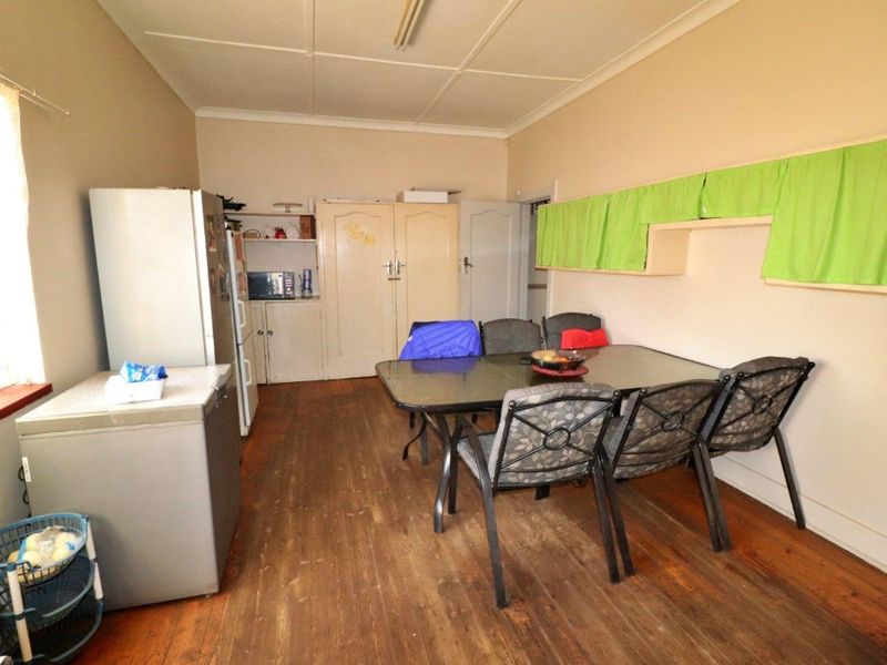 A dining area featuring timber flooring and built-in storage cupboards, offering a functional space with potential for modernization.