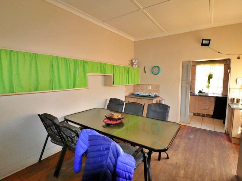 Open plan dining area featuring laminate flooring and access to a secondary kitchen space with built-in cabinetry and tiled splashbacks.