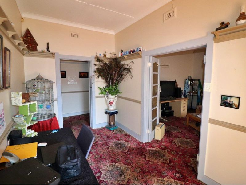 A living area featuring traditional picture rails, ceiling vents, and internal french doors, with dated carpet and wall finishes throughout.