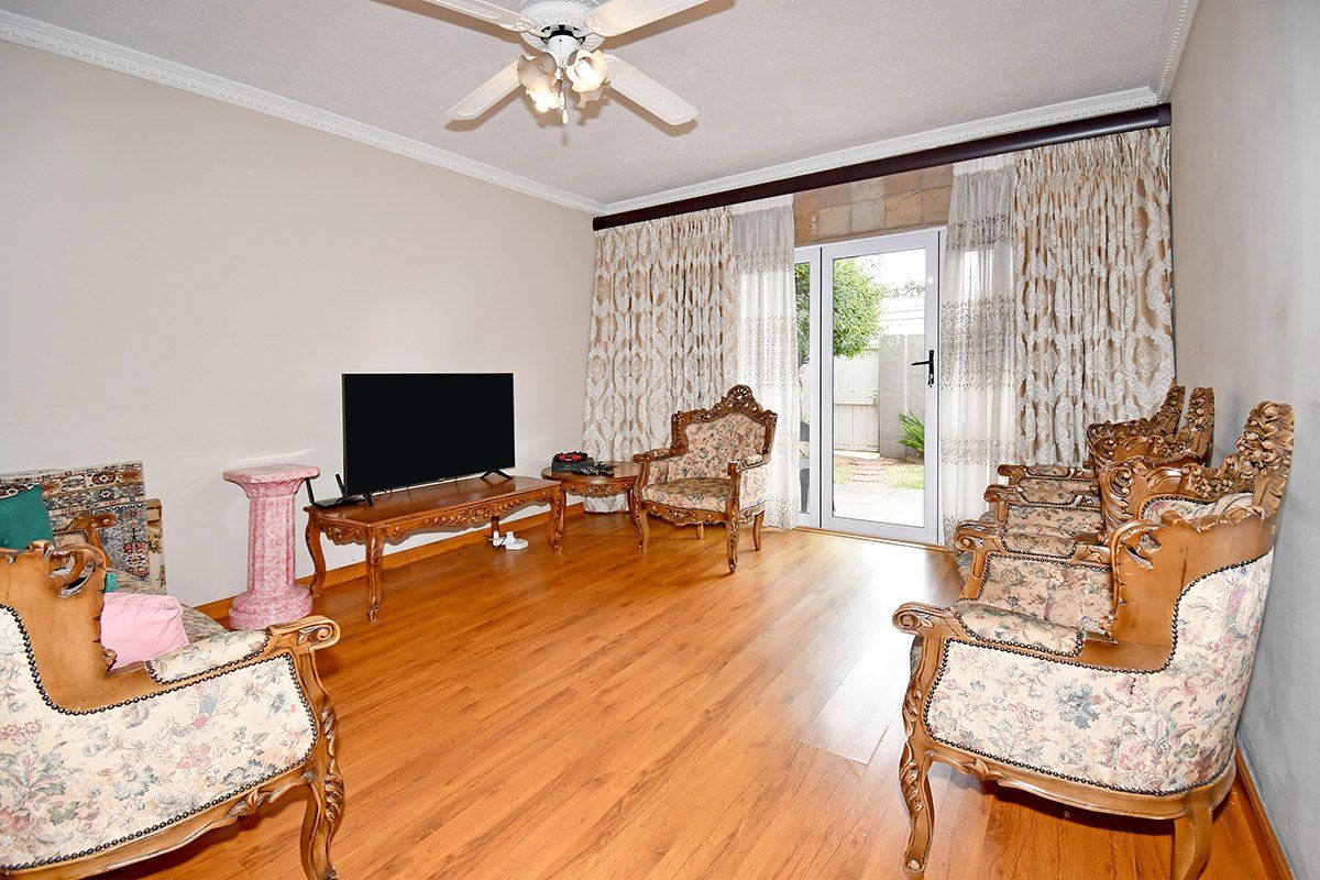 A living room featuring laminate flooring, crown molding, a ceiling fan, and a glass door providing access to the outdoor area.