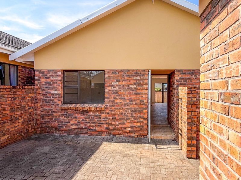 A private rear courtyard featuring face brick walls, paved flooring, and direct access into the townhouse interior.